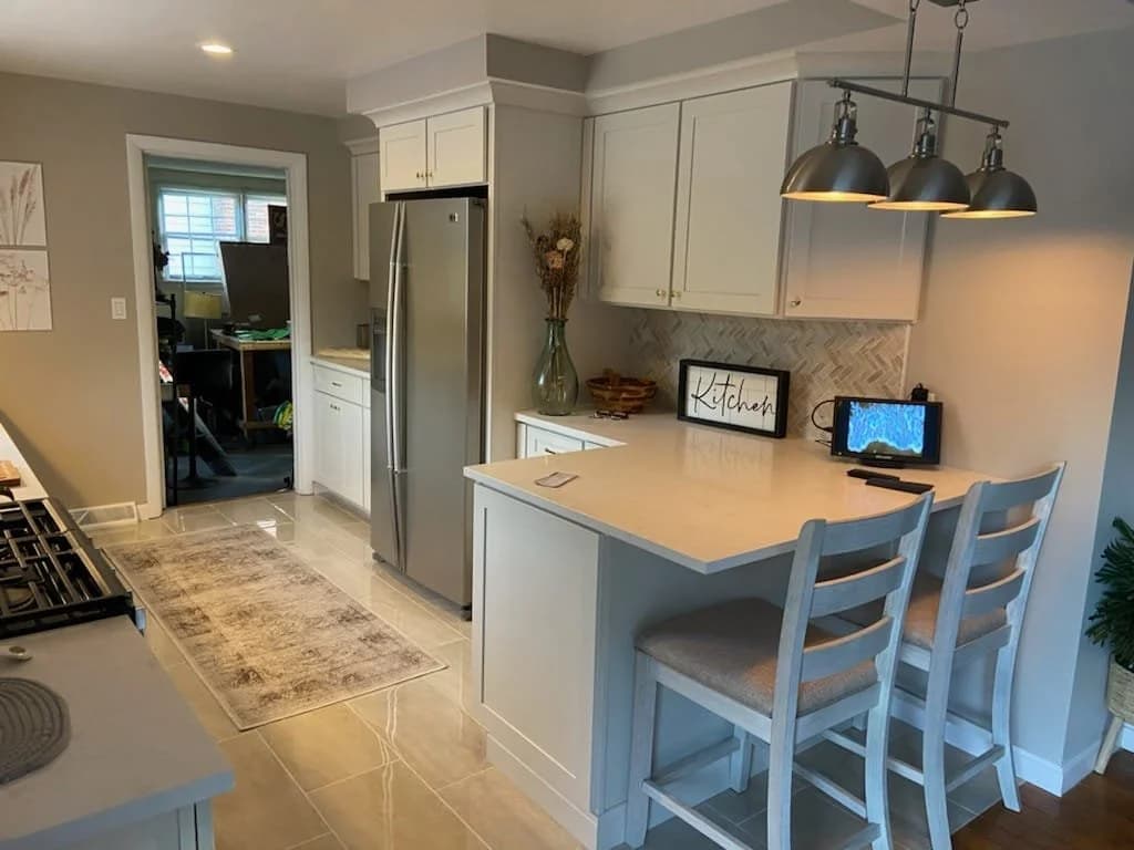 Remodeled kitchen with a quartz peninsula, shaker cabinets and pendant lighting
