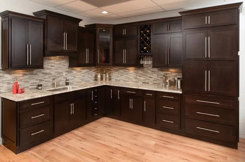 Dark shaker cabinetry with granite countertops, a tile backsplash and a built-in wine rack