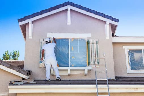 Painter masking and painting a stucco home exterior gable